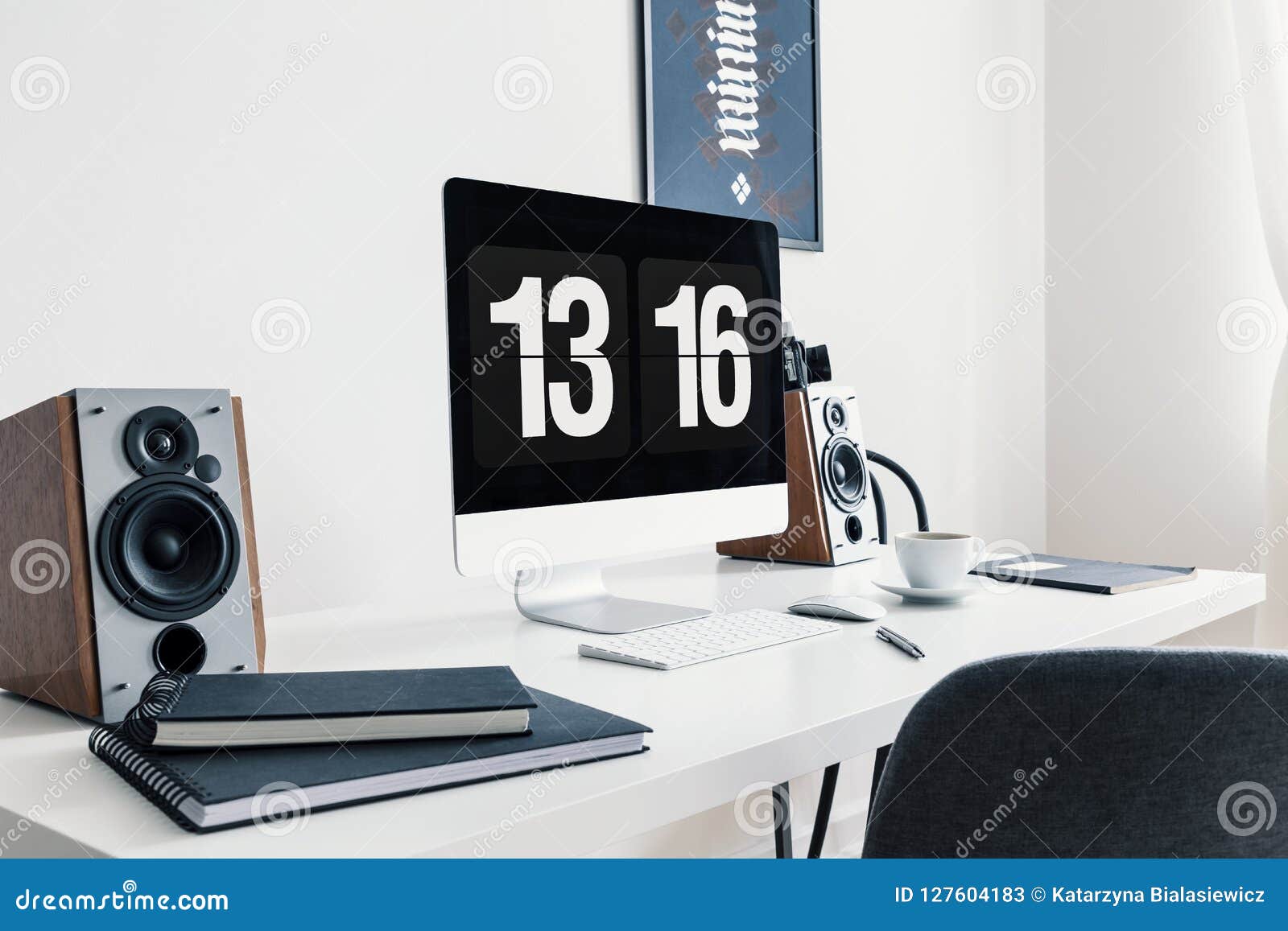 Close Up Of A White Desk With Spiral Notepads Speakers And A