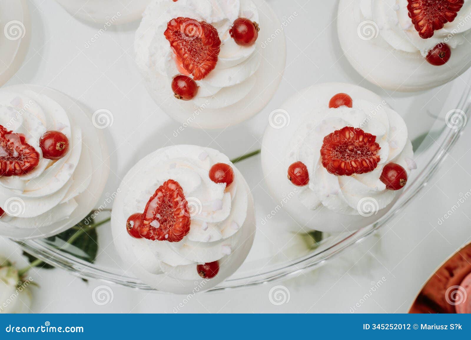 close-up of white meringue desserts topped with fresh raspberries