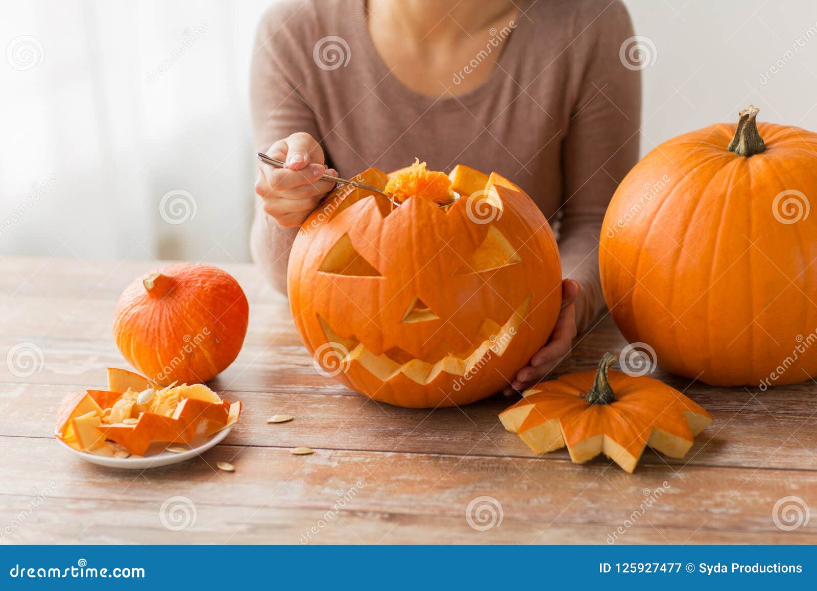 close up of woman carving halloween pumpkin