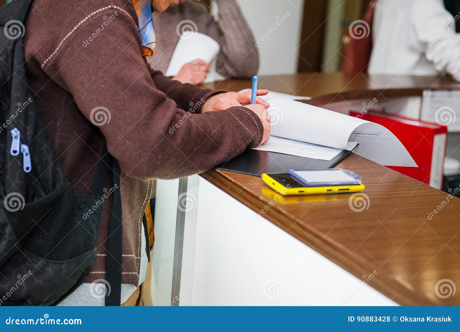 close up of a woman hand writing or signing in a document on a reception zone of clinic. selective focus