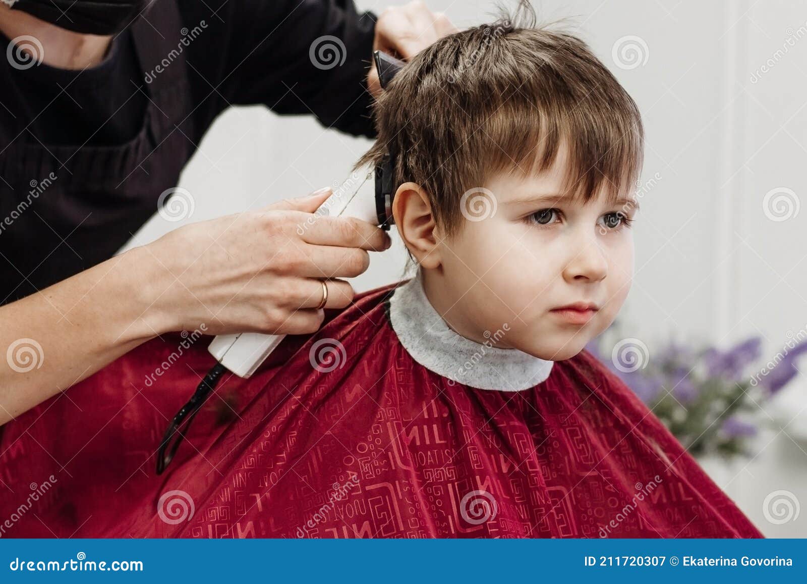 Barber's hands spray the little boy's hair with a spray gun. Stock