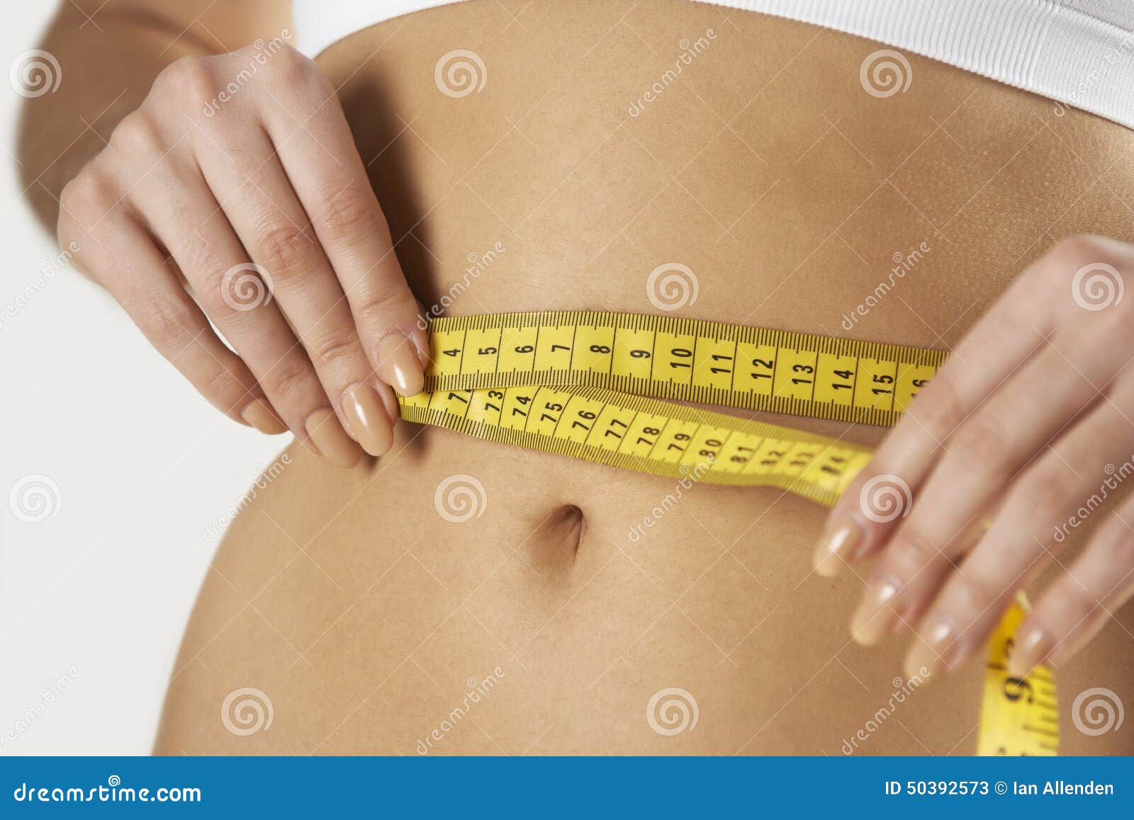 close-up of woman in underwear measuring waist with tape