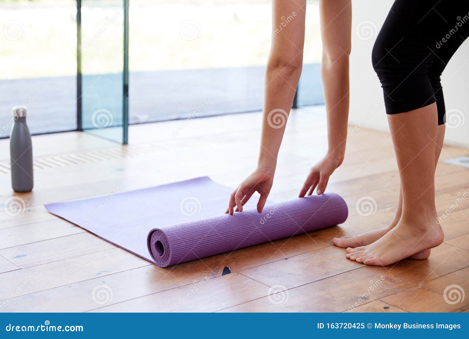 Closeup Of Athletic Woman Rolling Up Her Exercise Mat After