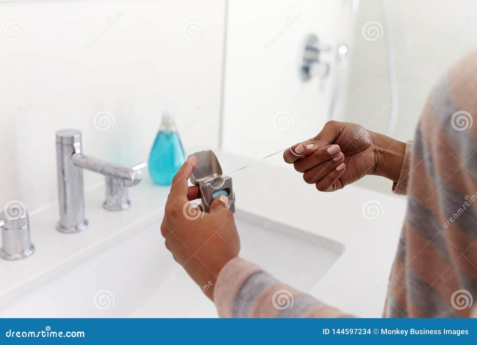 Close Up of Woman Using Dental Floss from Pack in Bathroom Stock Photo