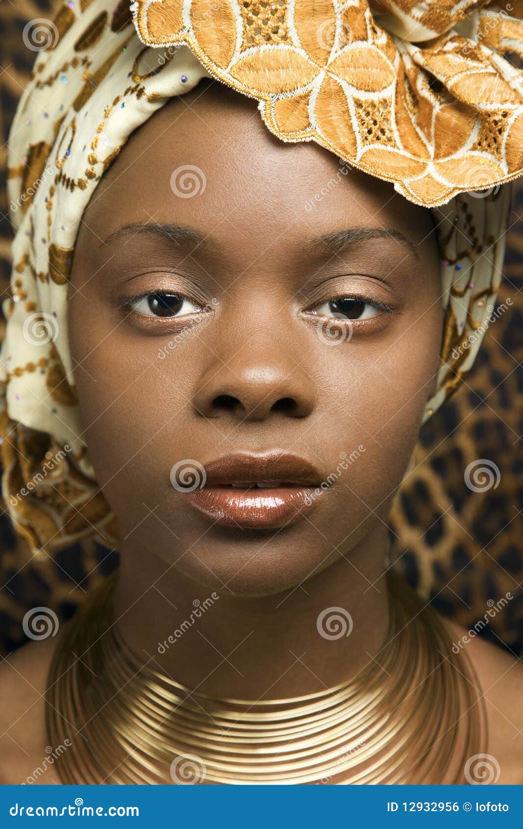 Close-up of Young African American Woman in Tradit. Close-up portrait of an African American woman wearing traditional African clothing in front of a patterned wall. Vertical format.