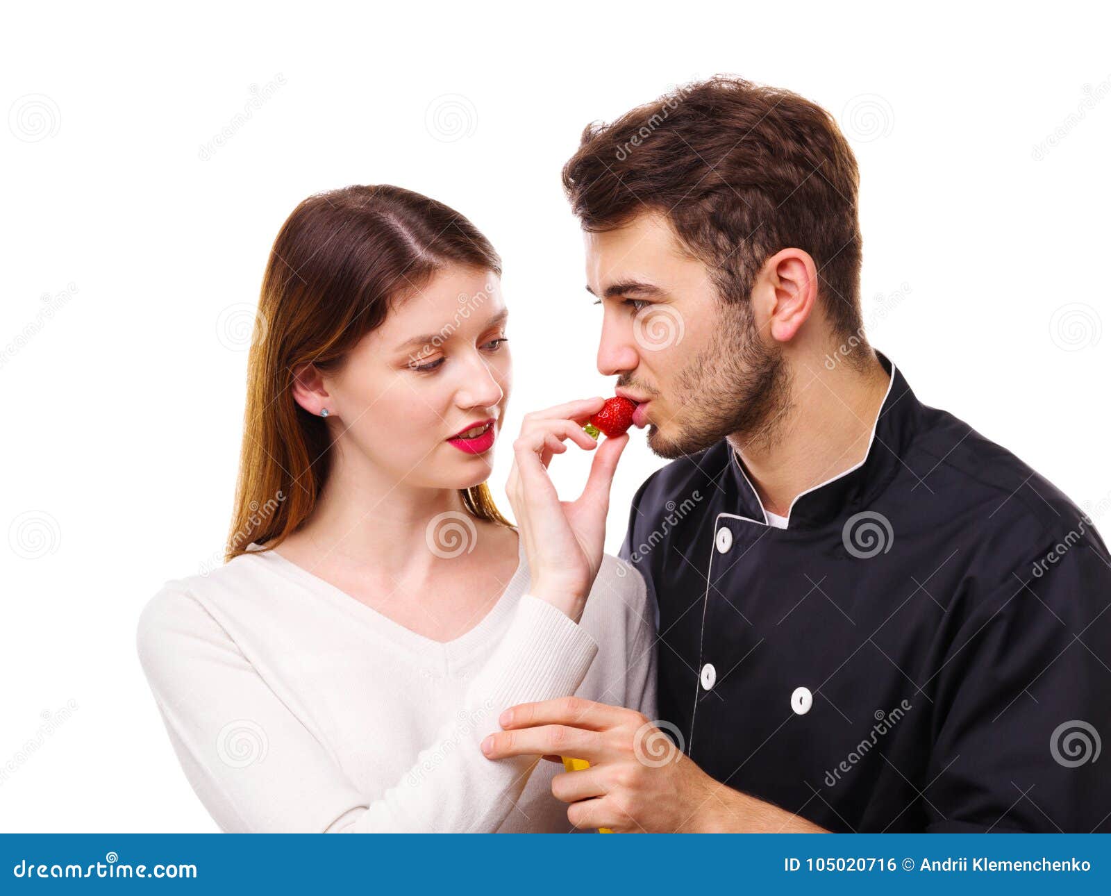 Close-up of a Girl Feeding a Guy with a Strawberry, on a White Background Stock Photo