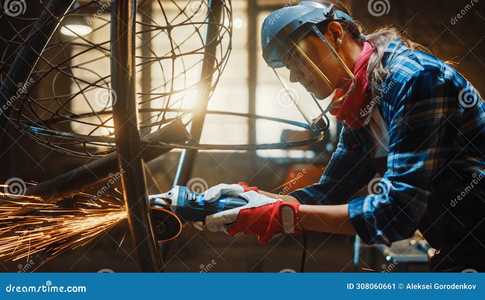 close up of young female fabricator in safety mask. she is grinding a metal tube sculpture with an
