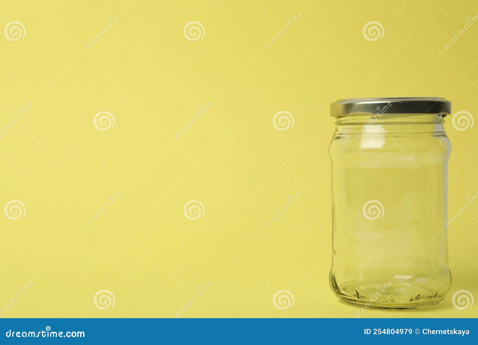 Closed Empty Glass Jar on Light Yellow Background, Space for Text Stock