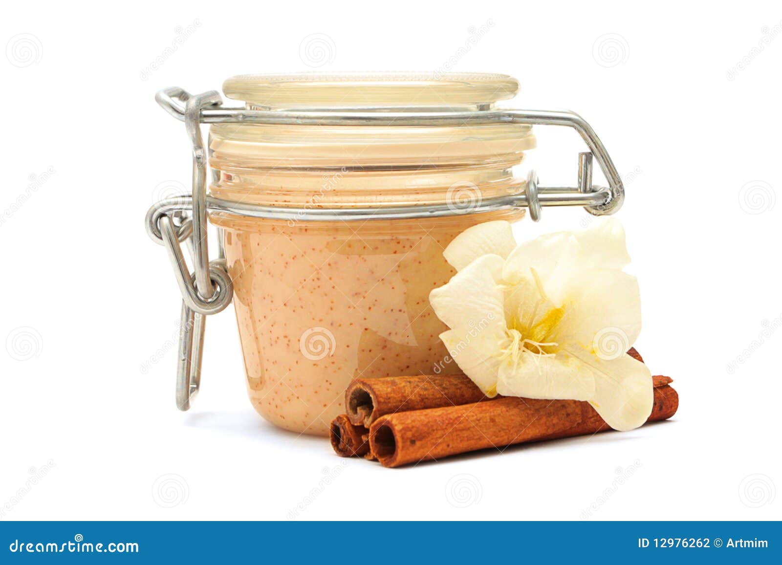 Closed jar with some creamy substance and cinnamon. Closed jar with some creamy substance, white flower and cinnamon on a white background