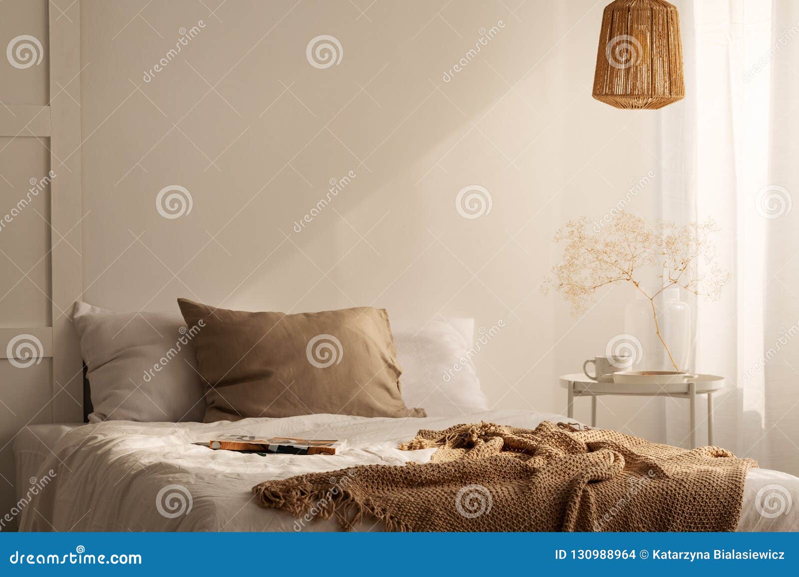 closeup of bed with beige blanket and linen pillow in minimal bedroom interior, real photo