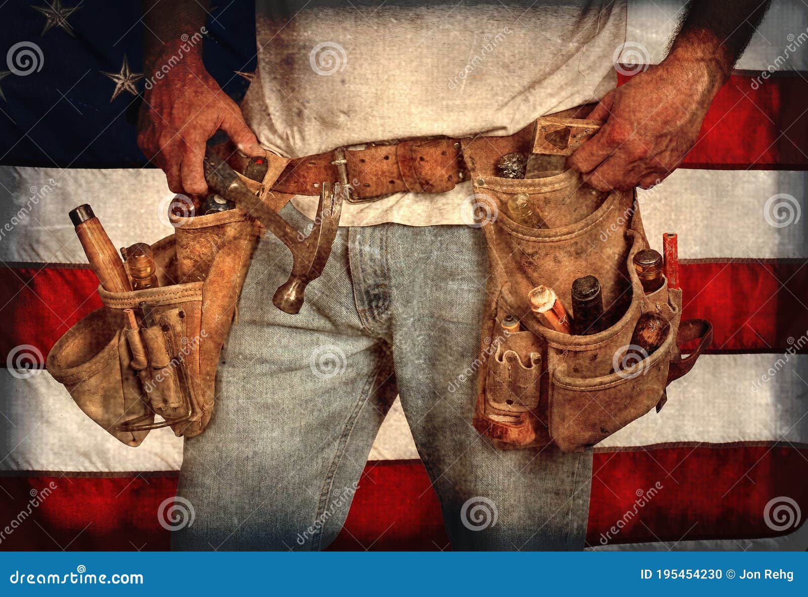 closeup carpenter wearing old, worn out leather toolbelt in front of american flag