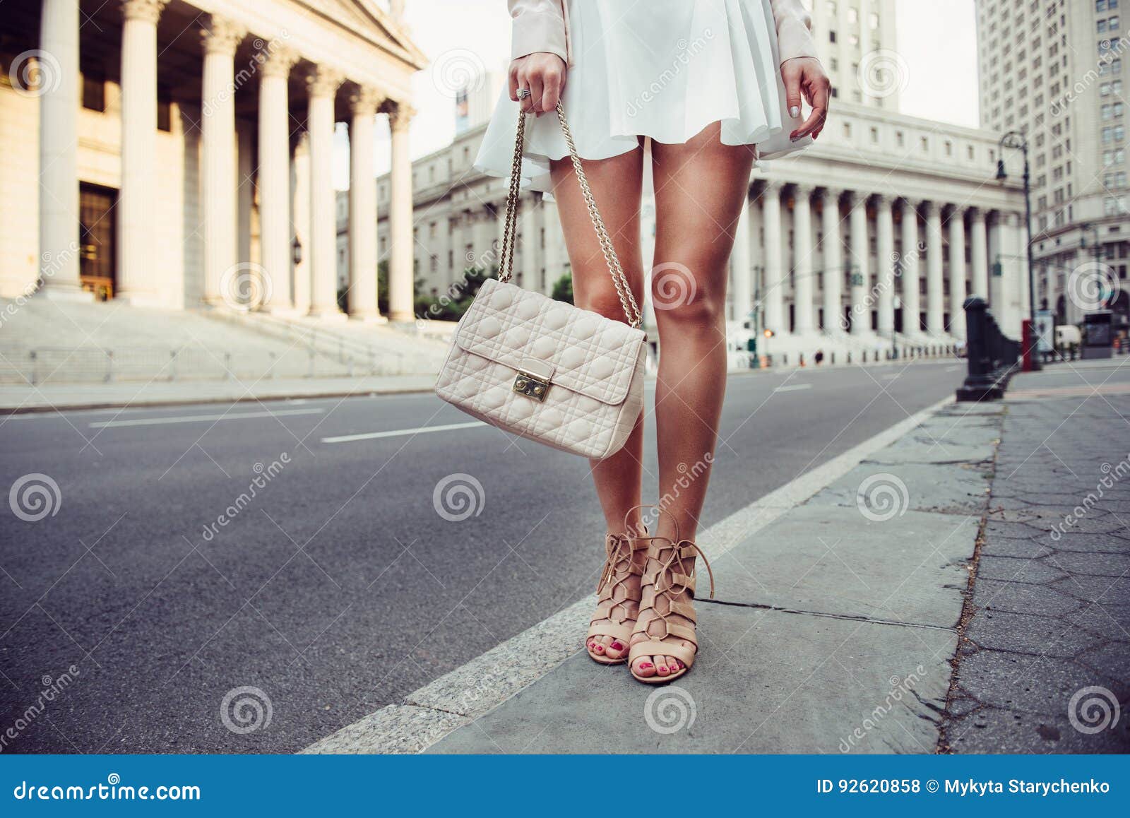 closeup details of summer female casual street style outfit with luxury bag, skirt and high-heels. fashionable girl standing at ne