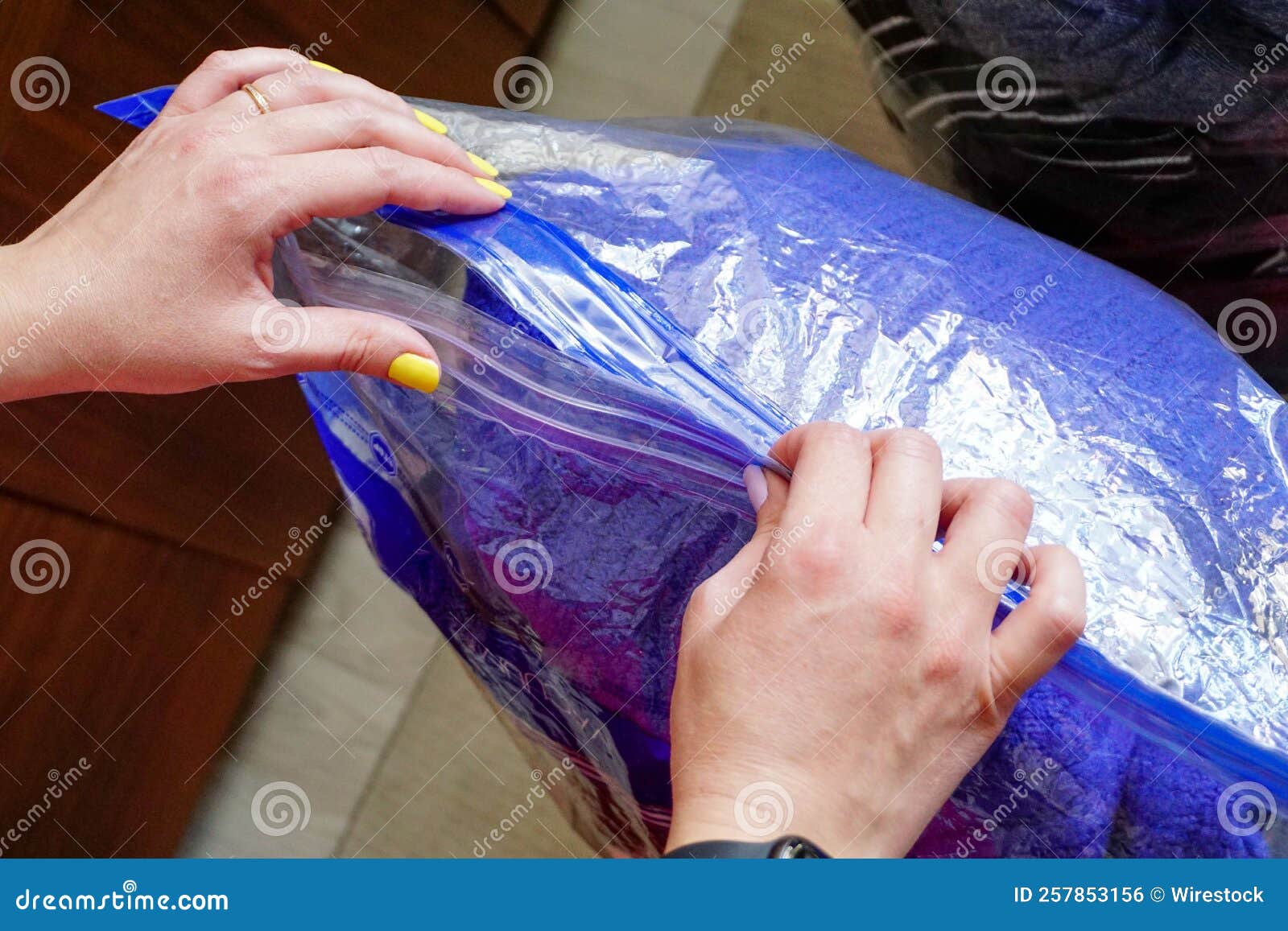 Closeup Of A Female Closing A Big Plastic Zip Lock Bag For Clothes closeup-of-a-female-closing-a-big-plastic-zip-lock-bag-for-clothes