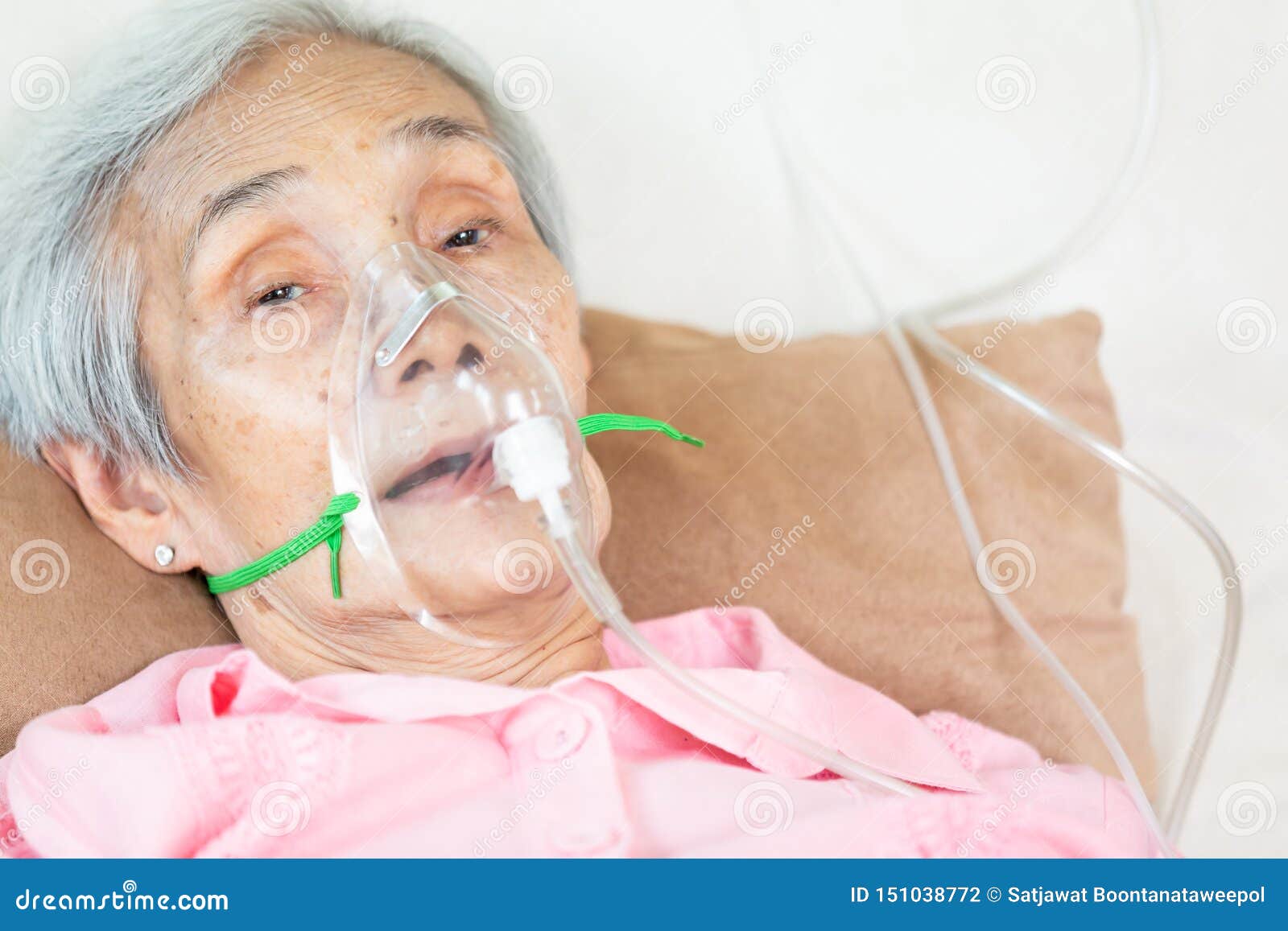 closeup of female senior patient putting inhalation or oxygen mask in hospital bed or home,sick elderly asian woman undergoing