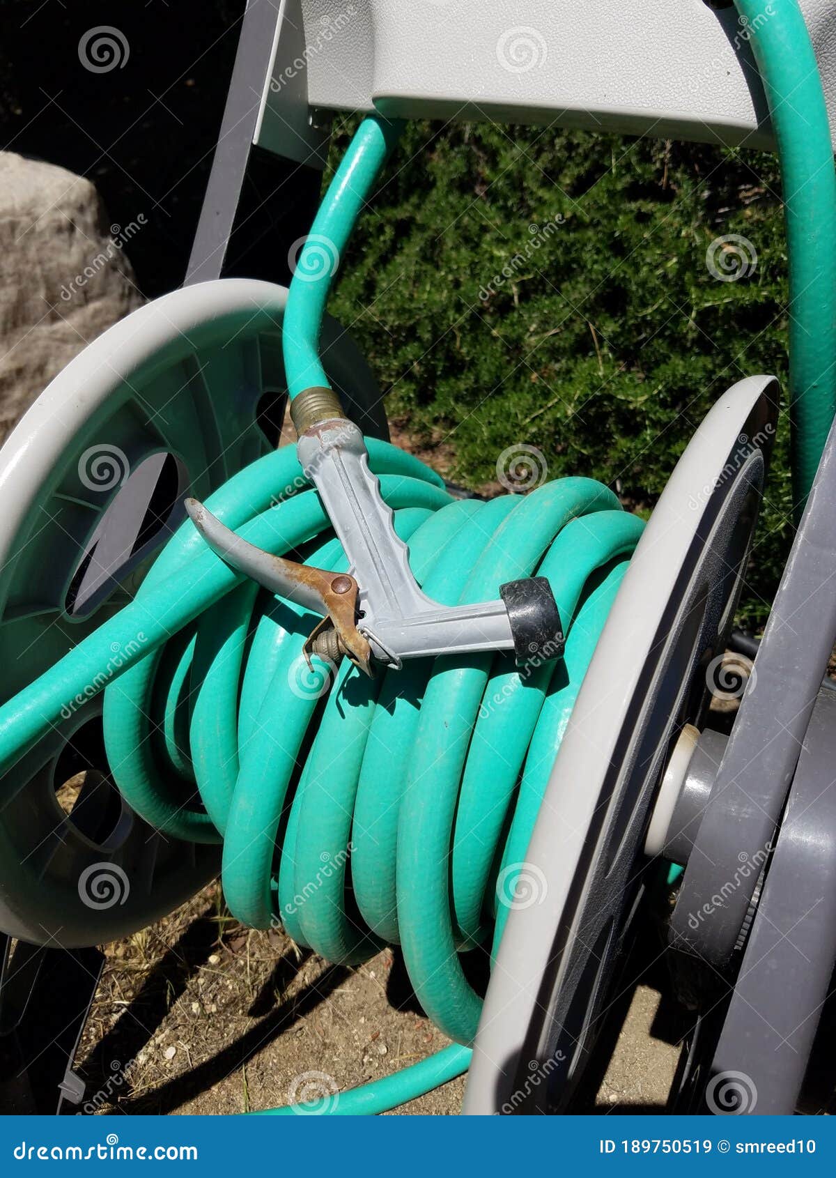 Closeup of Green Rubber Hose on Hose Reel with Spray Nozzle Stock