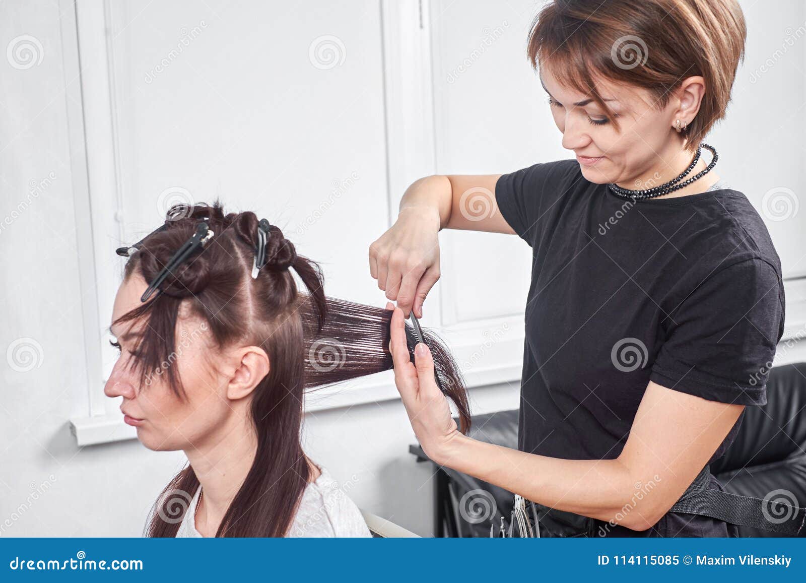 closeup of hair dresser combing client`s hair in salon