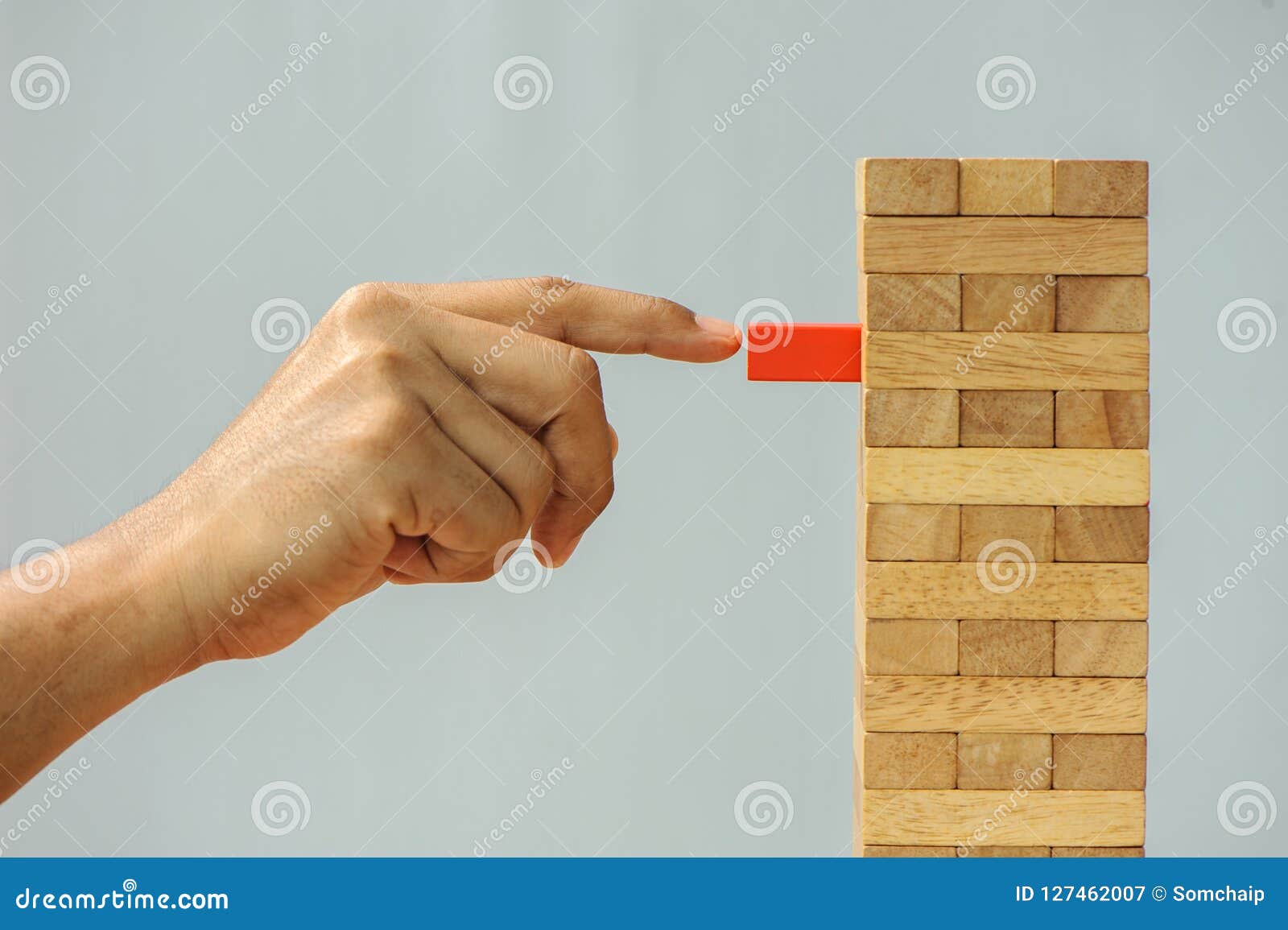 closeup hand man take one block on the tower from wooden blocks,