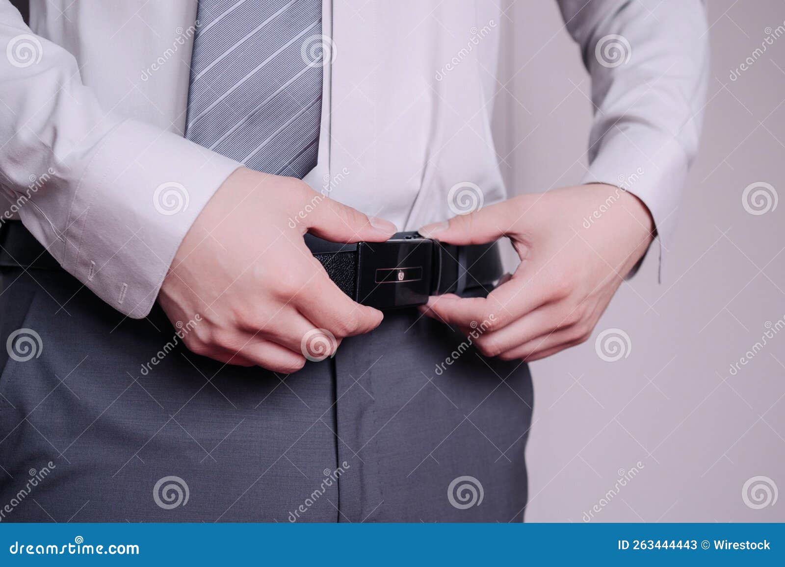 closeup of the hands of a groom fixing his belt