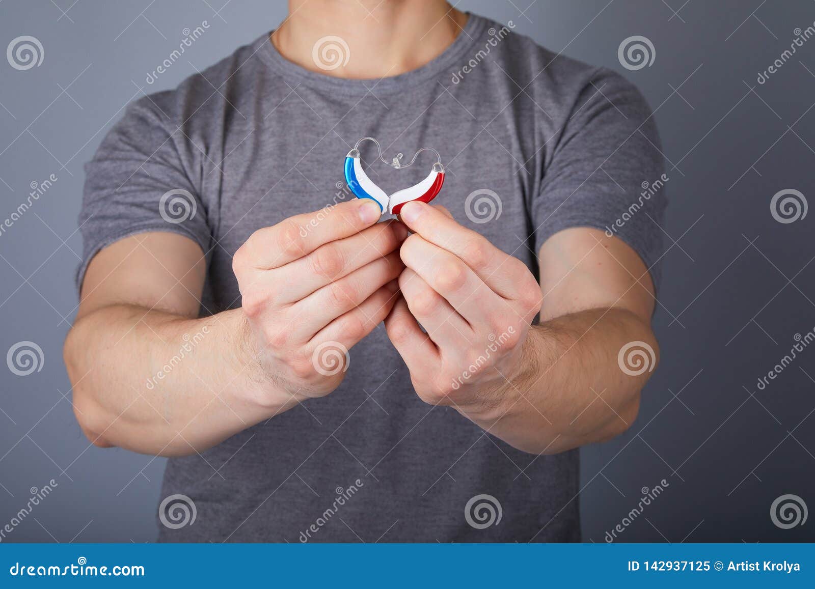 closeup of hands holding small inconspicuous hearing aids in heart 