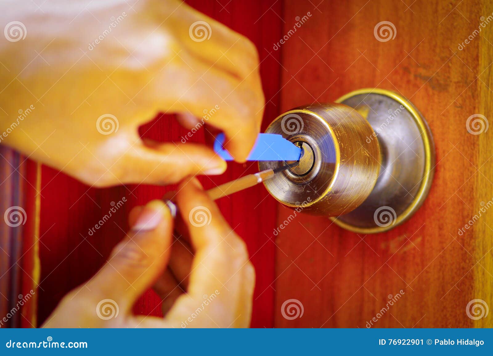 Closeup Hands of Locksmith Using Metal Pick Tools To Open Locked Door