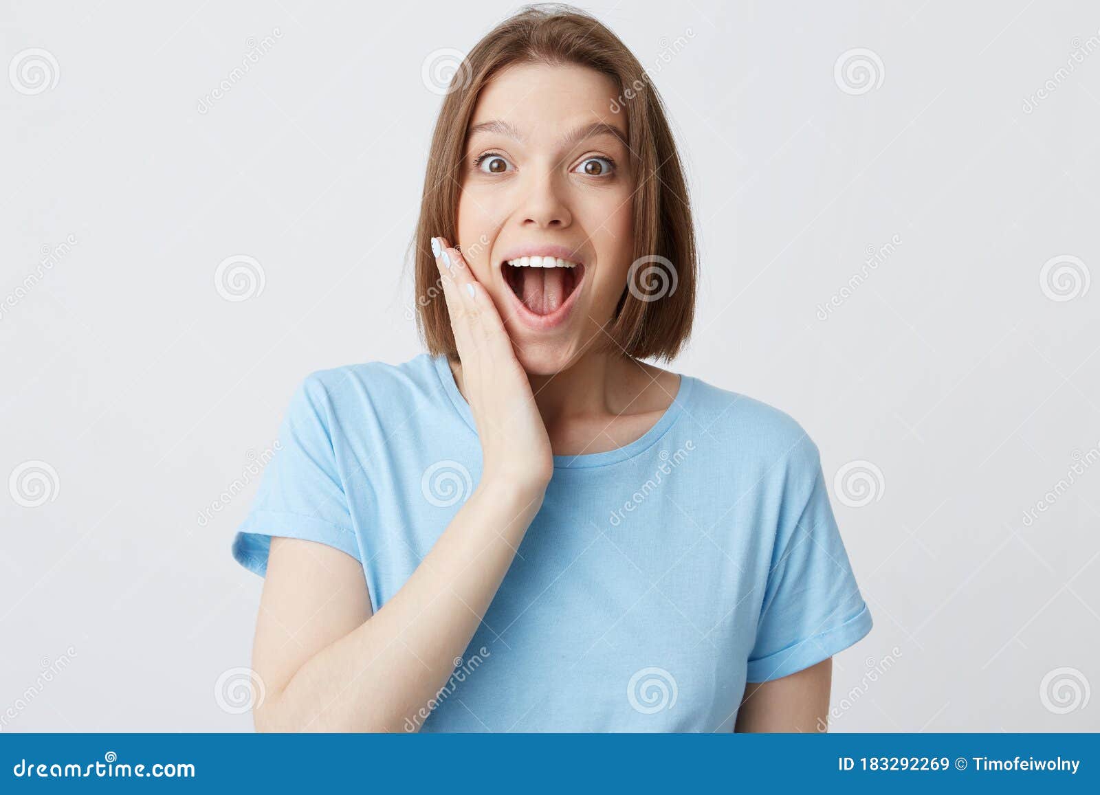 Closeup Of Happy Excited Attractive Young Woman In Blue T Shirt With Opened Mouth Touching Her 