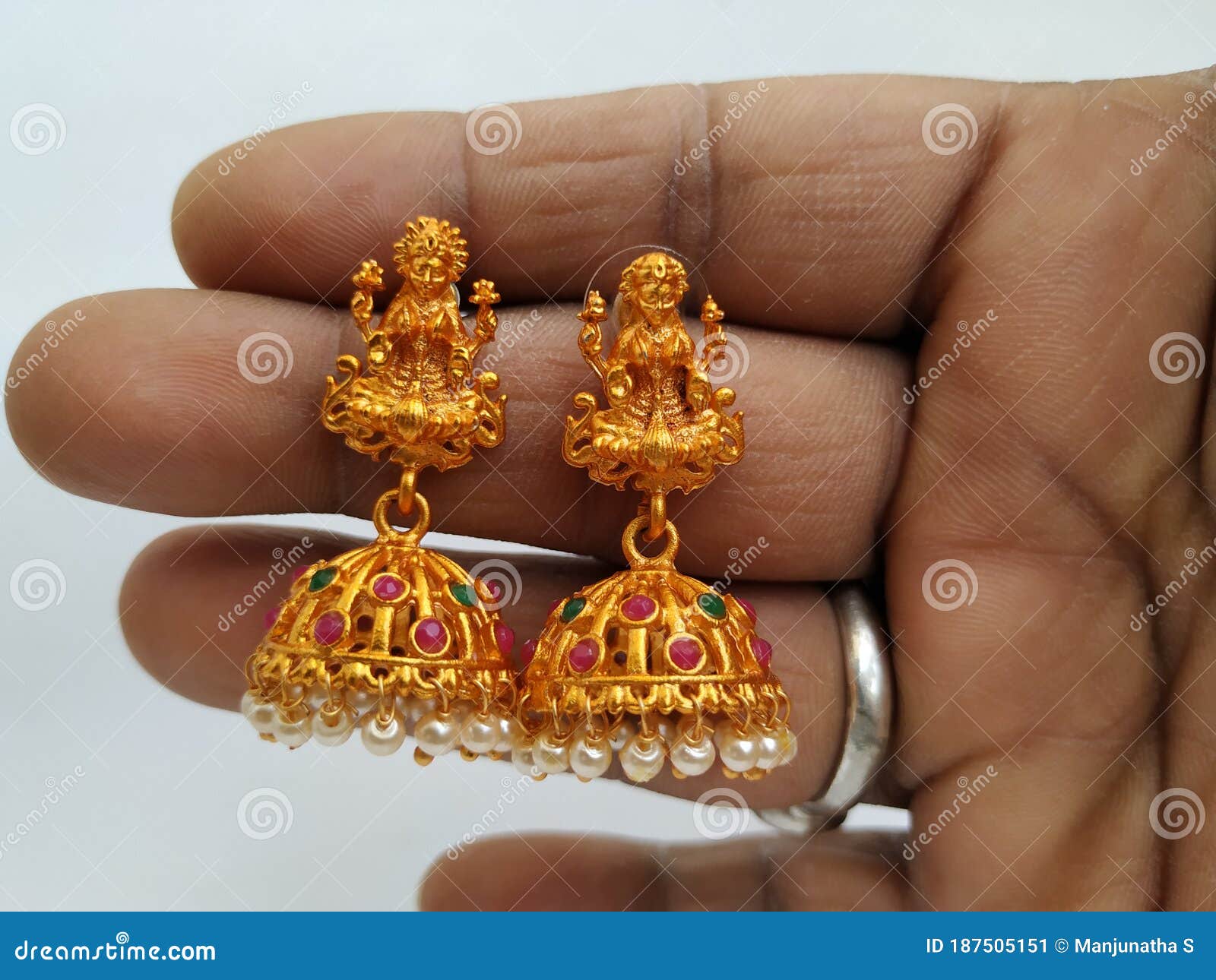 closeup holding goddess lakshmi statues golden traditional hand crafted ear ring stones gems isolated white 187505151