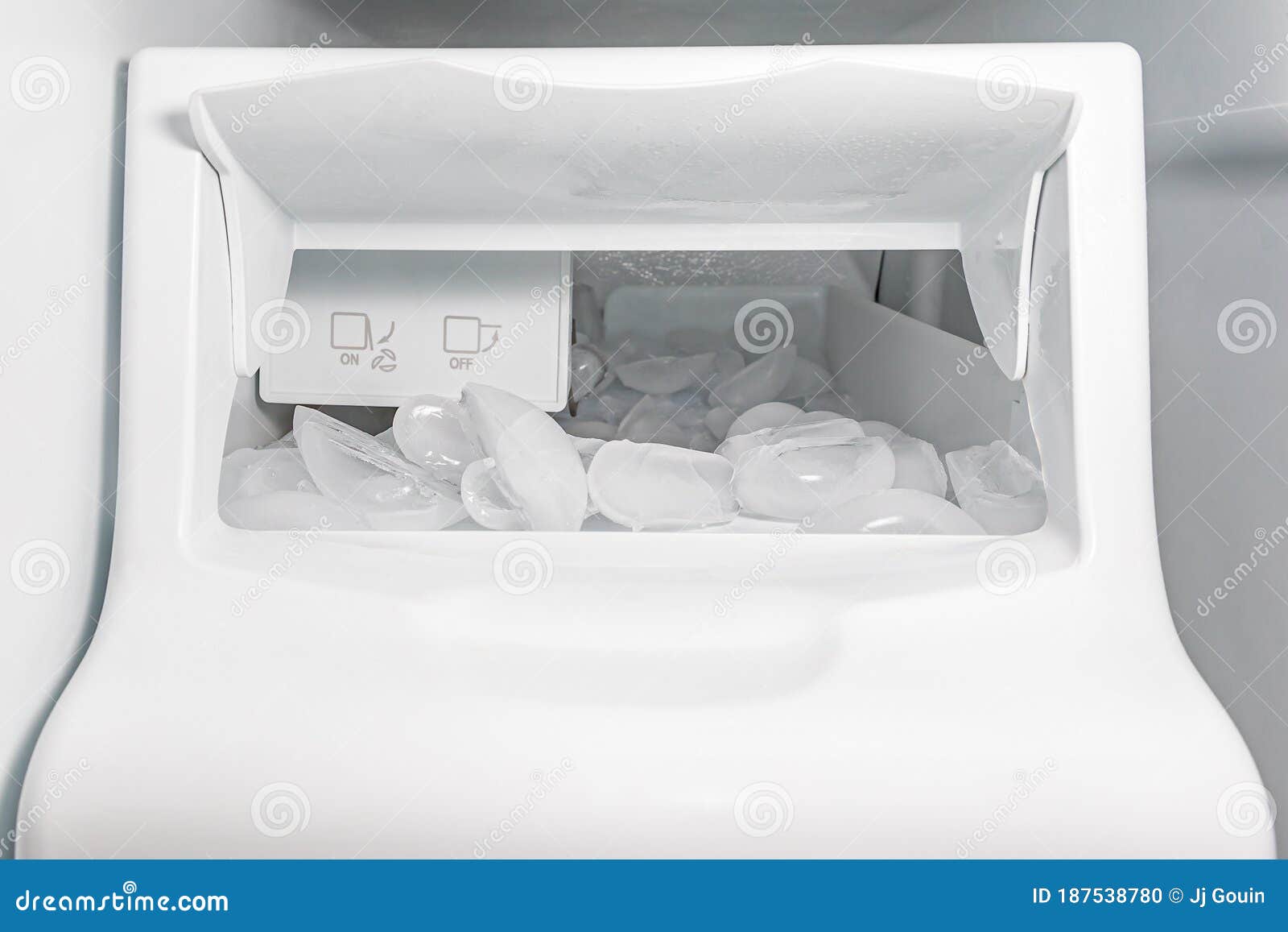 closeup of ice maker, ice machine in refrigerator with ice cubes