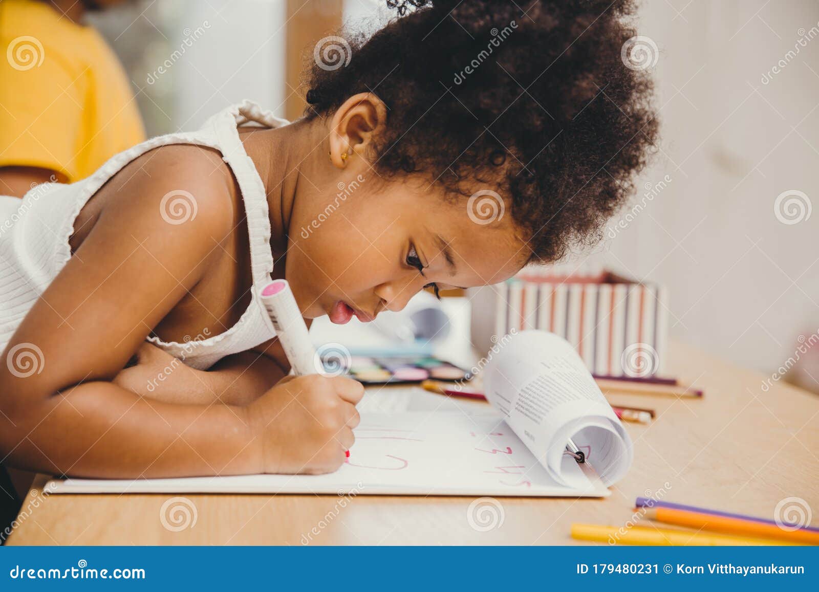 closeup little child girl black skin writing doing homework at home