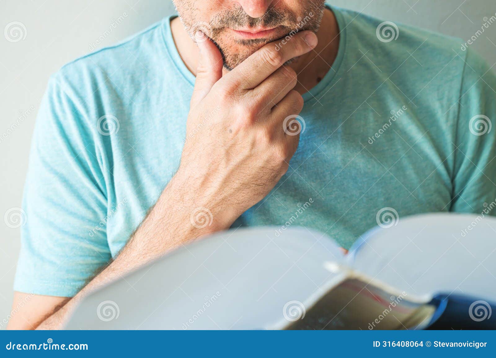 closeup of male reading book and stroking chin