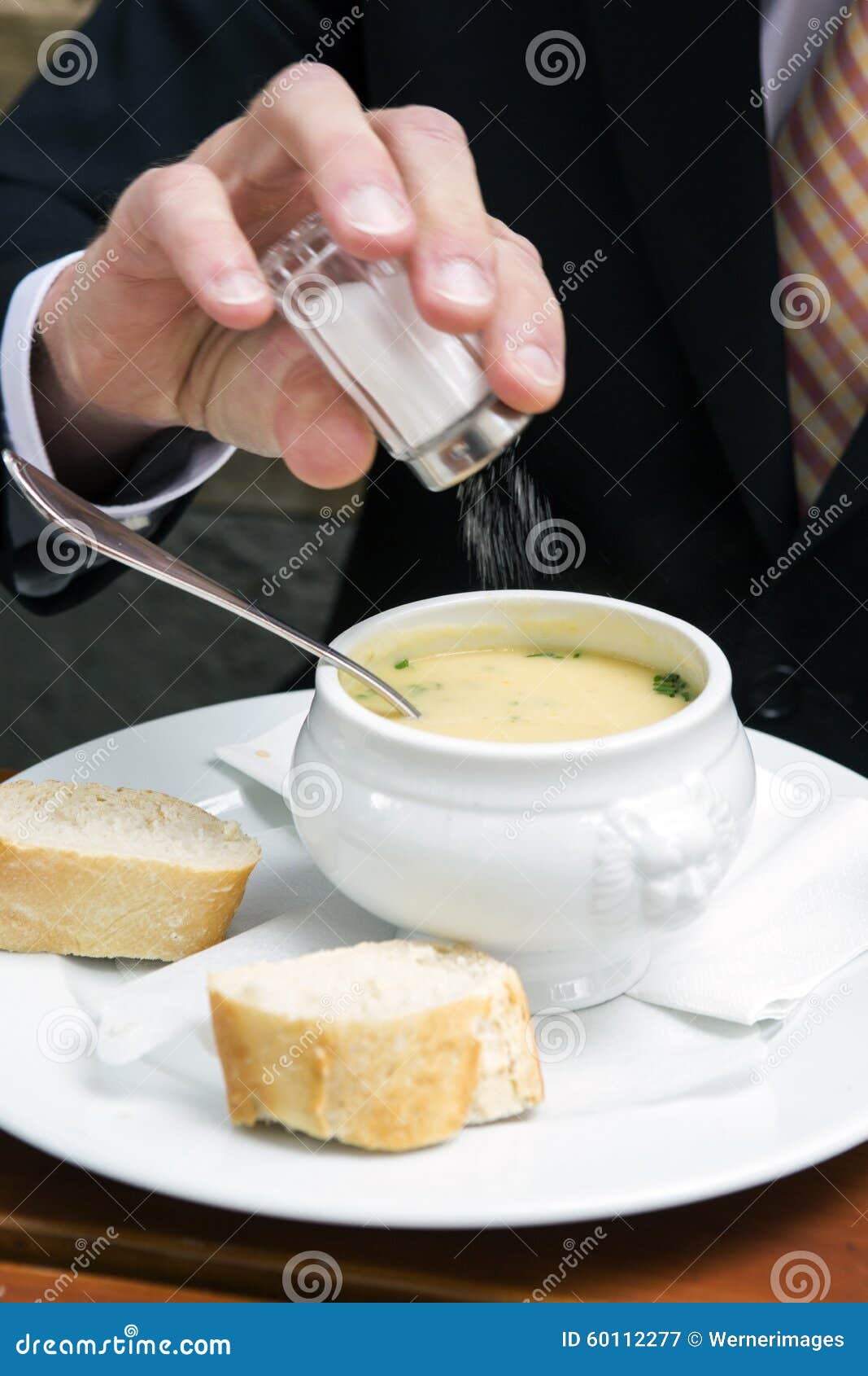 Closeup of man putting salt in a bowl of soup