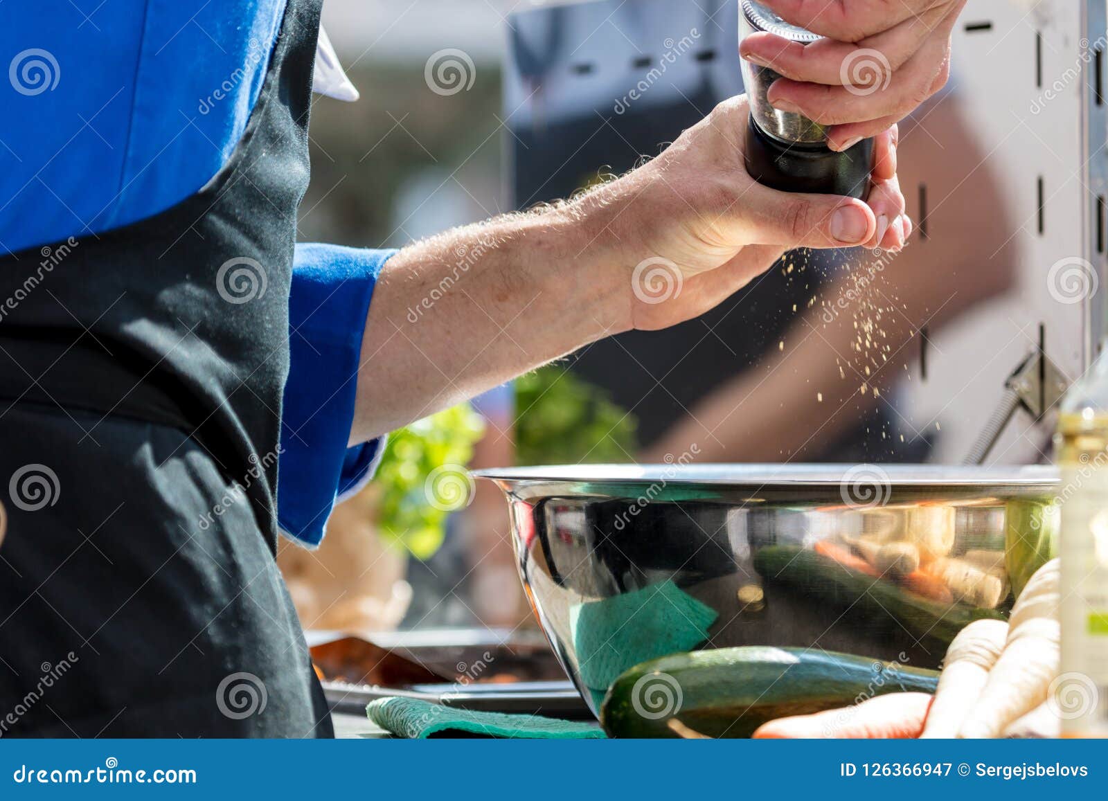 Closeup Mid Section of a Chef Putting Salt and Pepper in the Kitchen