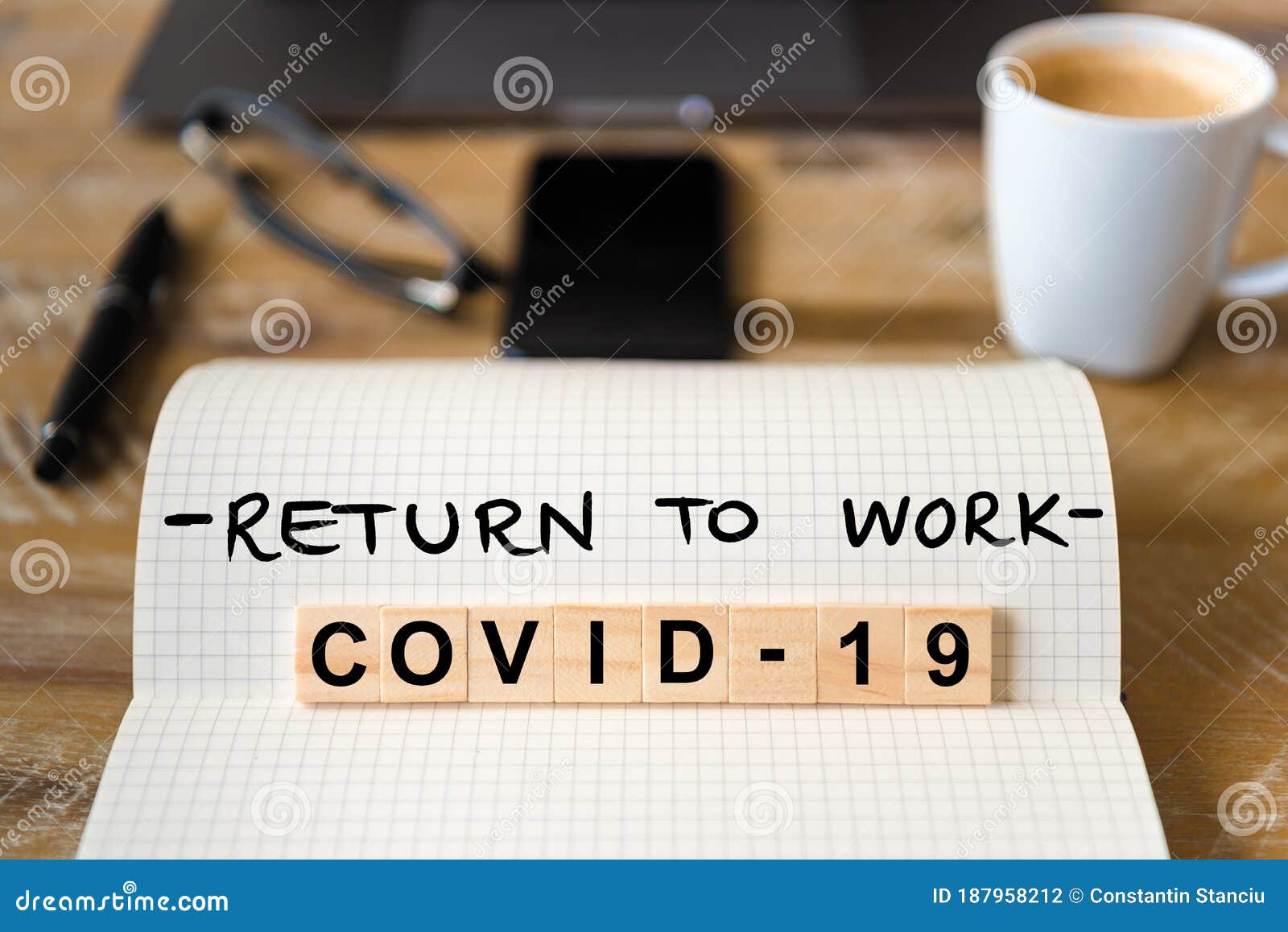 closeup on notebook over wood table background, focus on wooden blocks with letters making covid-19 return to work writing
