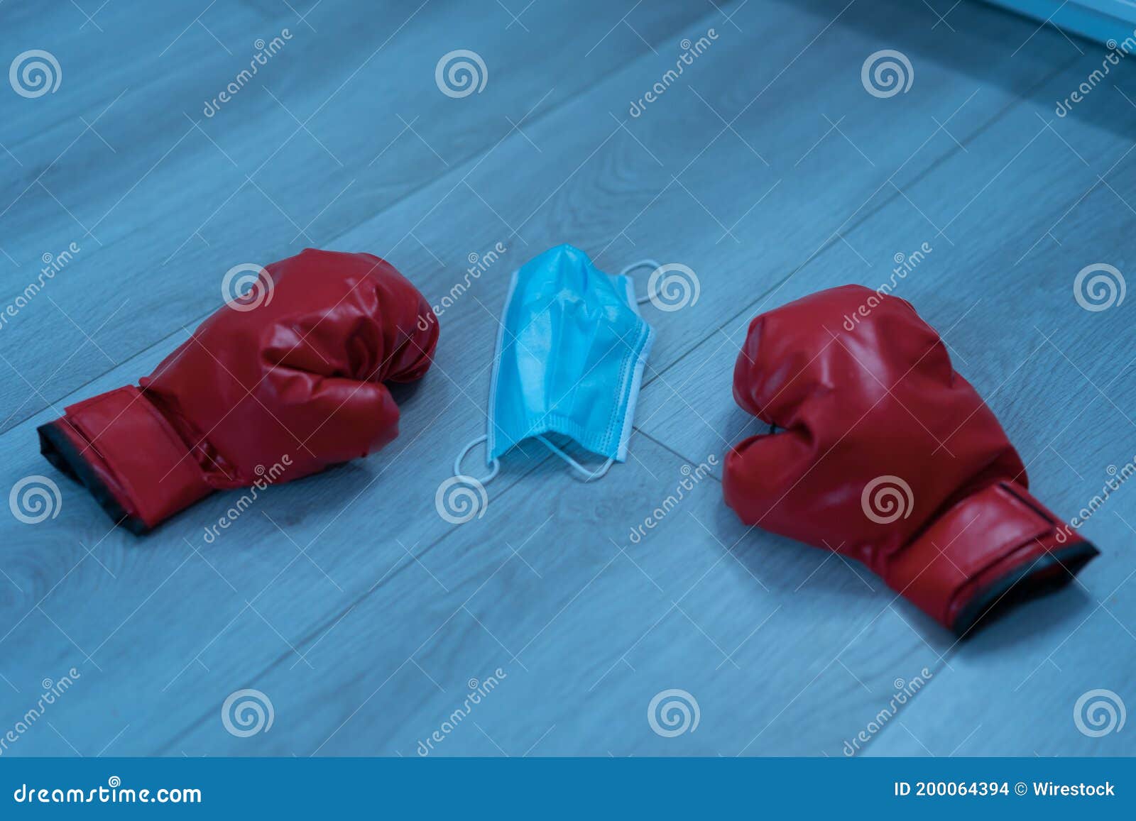 red leather boxing gloves and a medical mask on a wooden background - pandemic sports concept