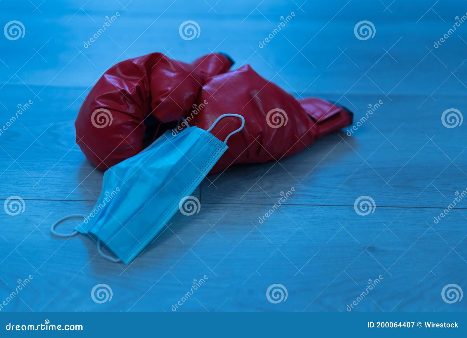 red leather boxing gloves and a medical mask on a wooden background - pandemic sports concept