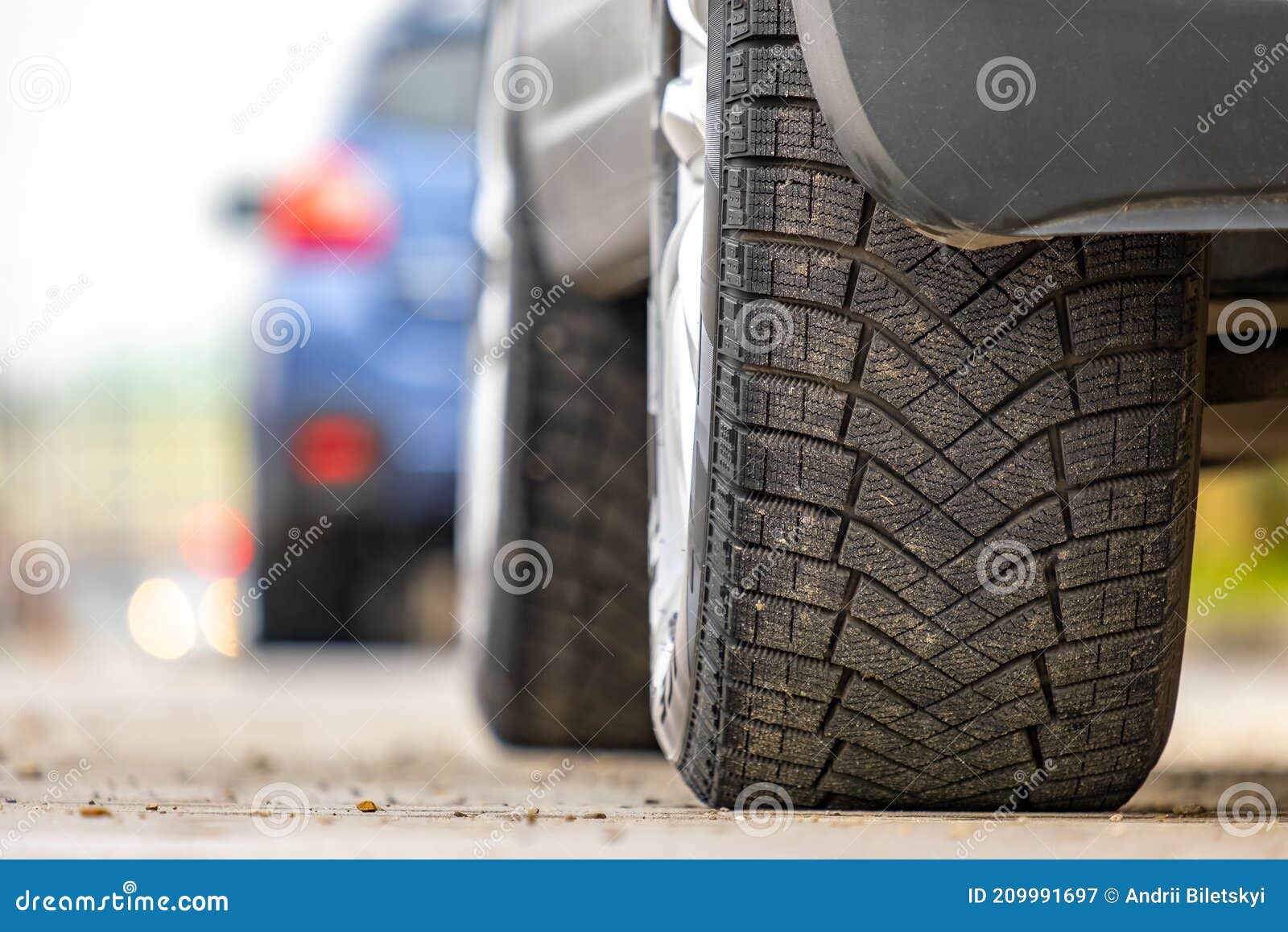 closeup of parked car on a city street side with new winter rubber tires