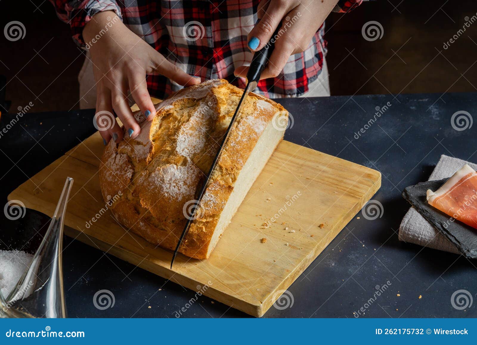 Closeup of a Person Cutting a Loaf of Bread on a Wooden Board for ...