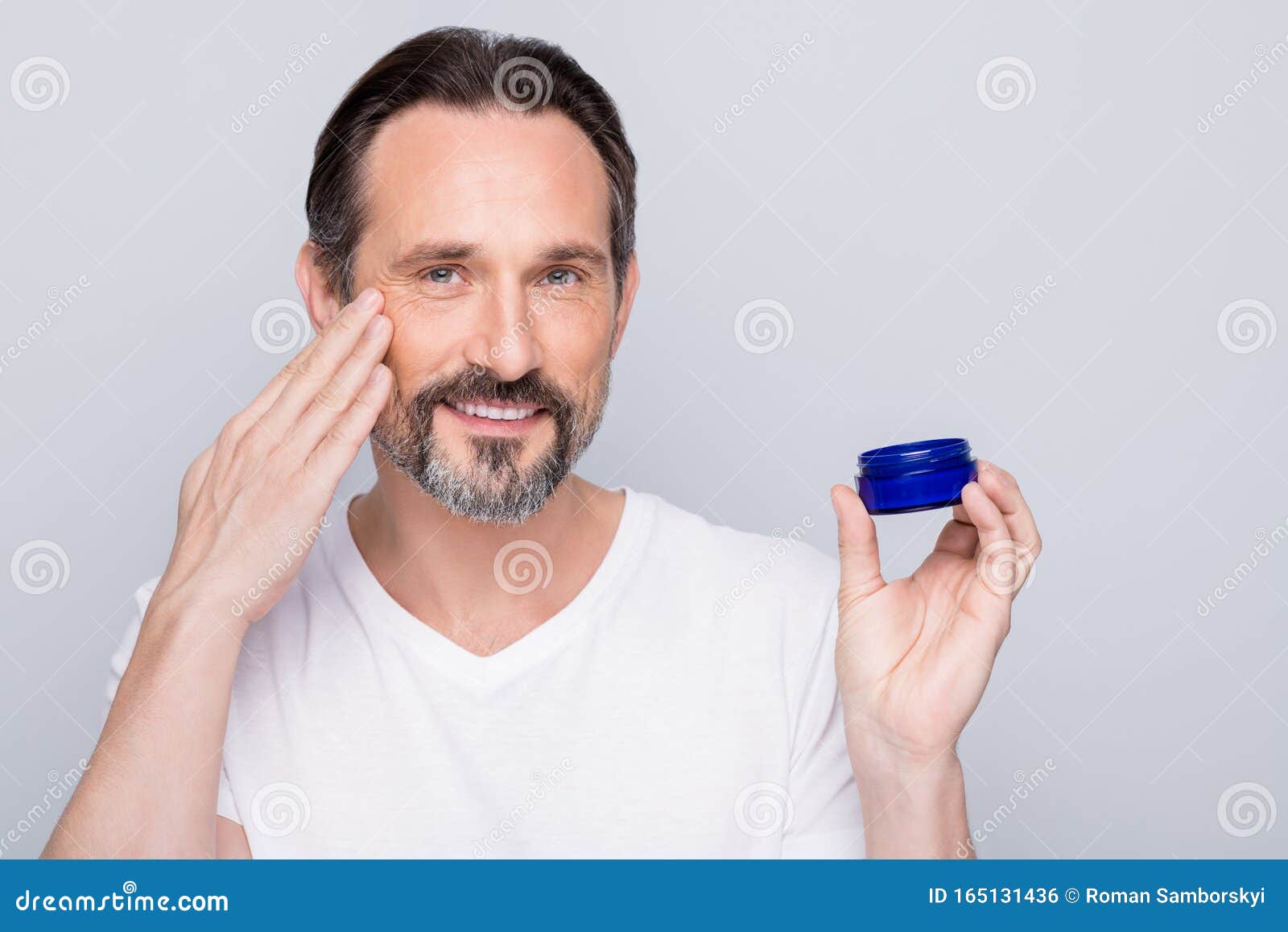 closeup photo of mature macho guy holding new night cream applying cheek skin metrosexual want get rid of wrinkles wear