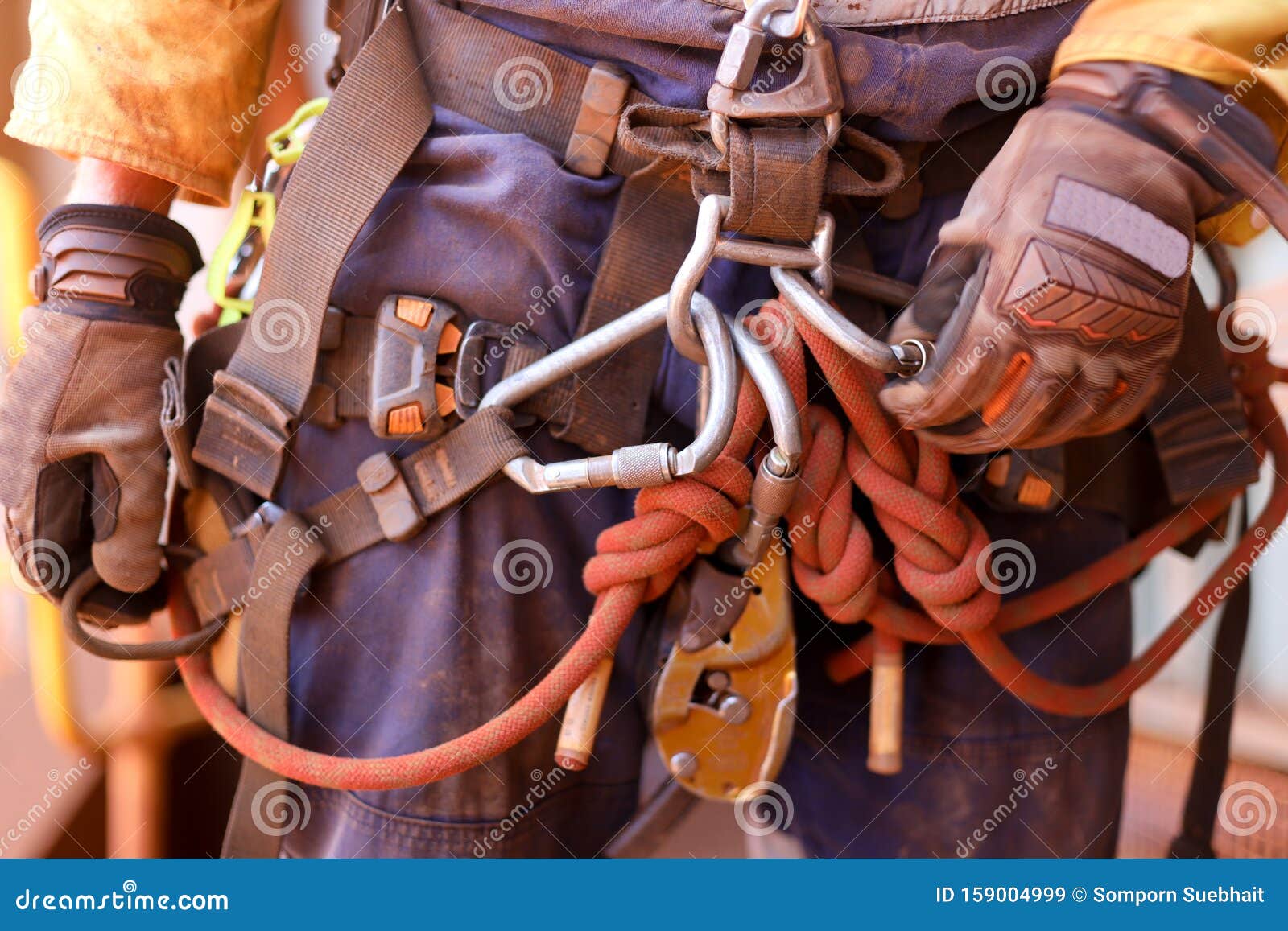 rope access worker wearing full safety harness inspecting clocking karabiner on a chair prior to abseiling