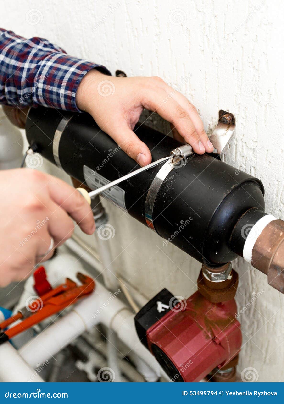 Closeup of Plumber Screwing Clamp Connecting Two Pipes Stock Photo