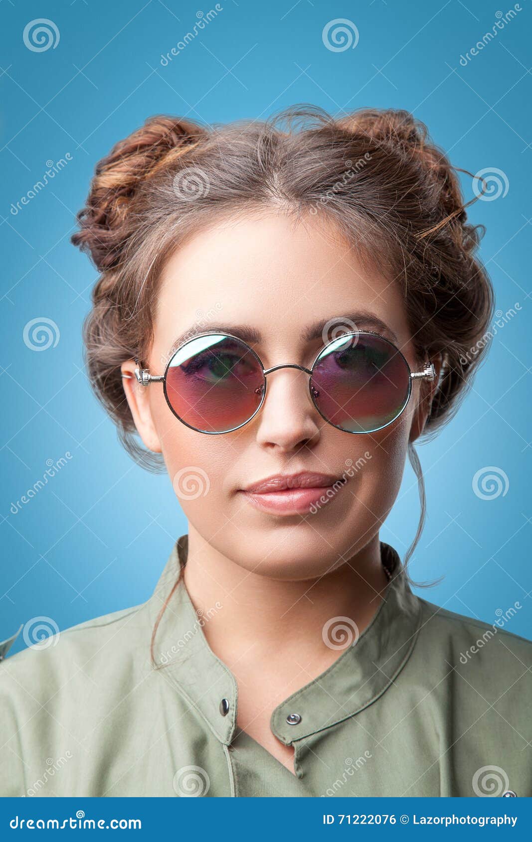 closeup portrait beautiful trendy hipster girl hair buns wearing round sunglasses green coat blue background youth 71222076