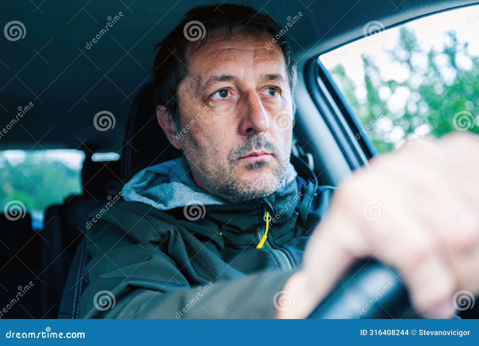 closeup portrait of cautious male driver gripping the steering wheel and driving a car on a road trip