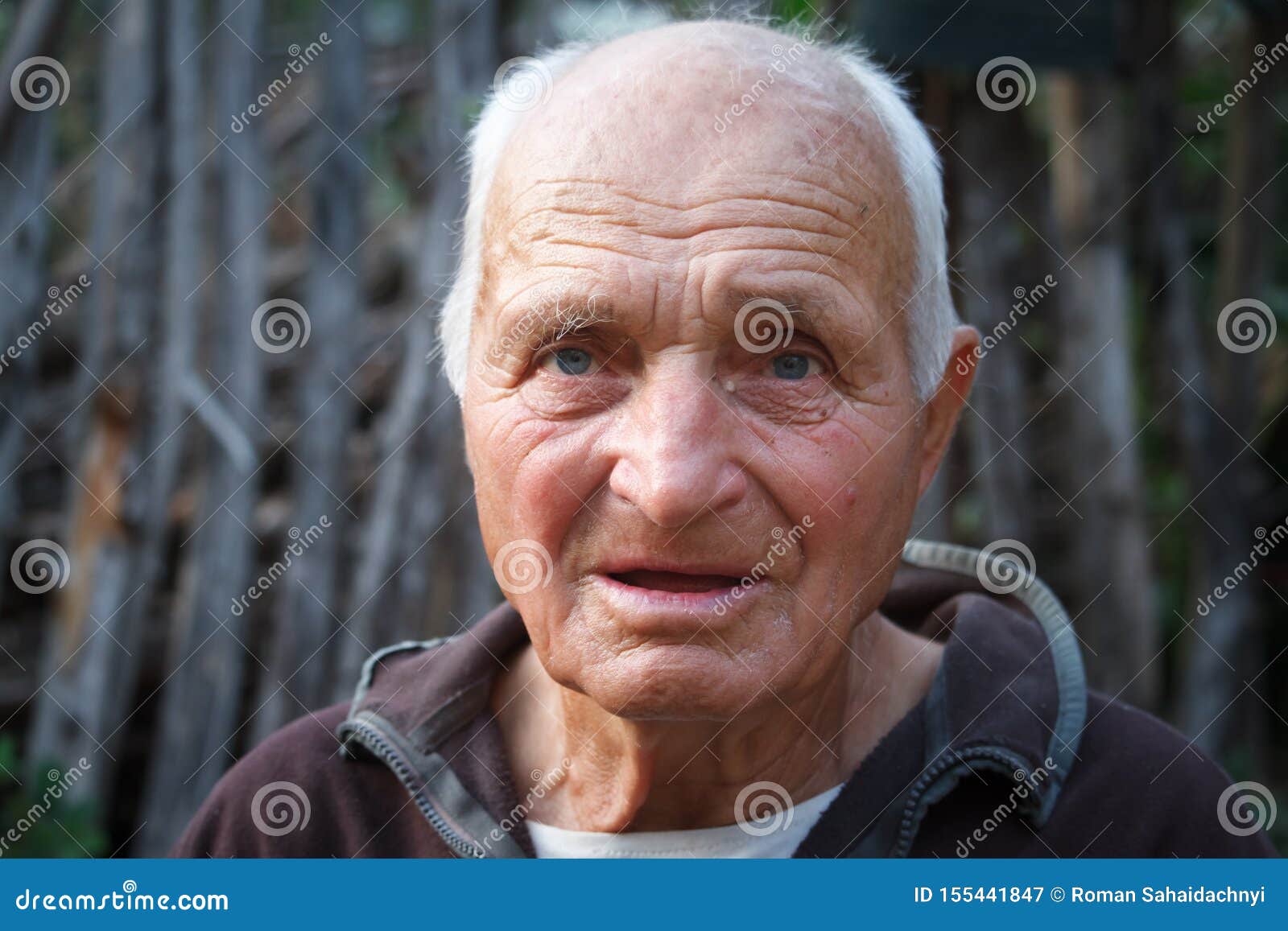 close-up portrait of a very old man against the background of wattle, selective focus