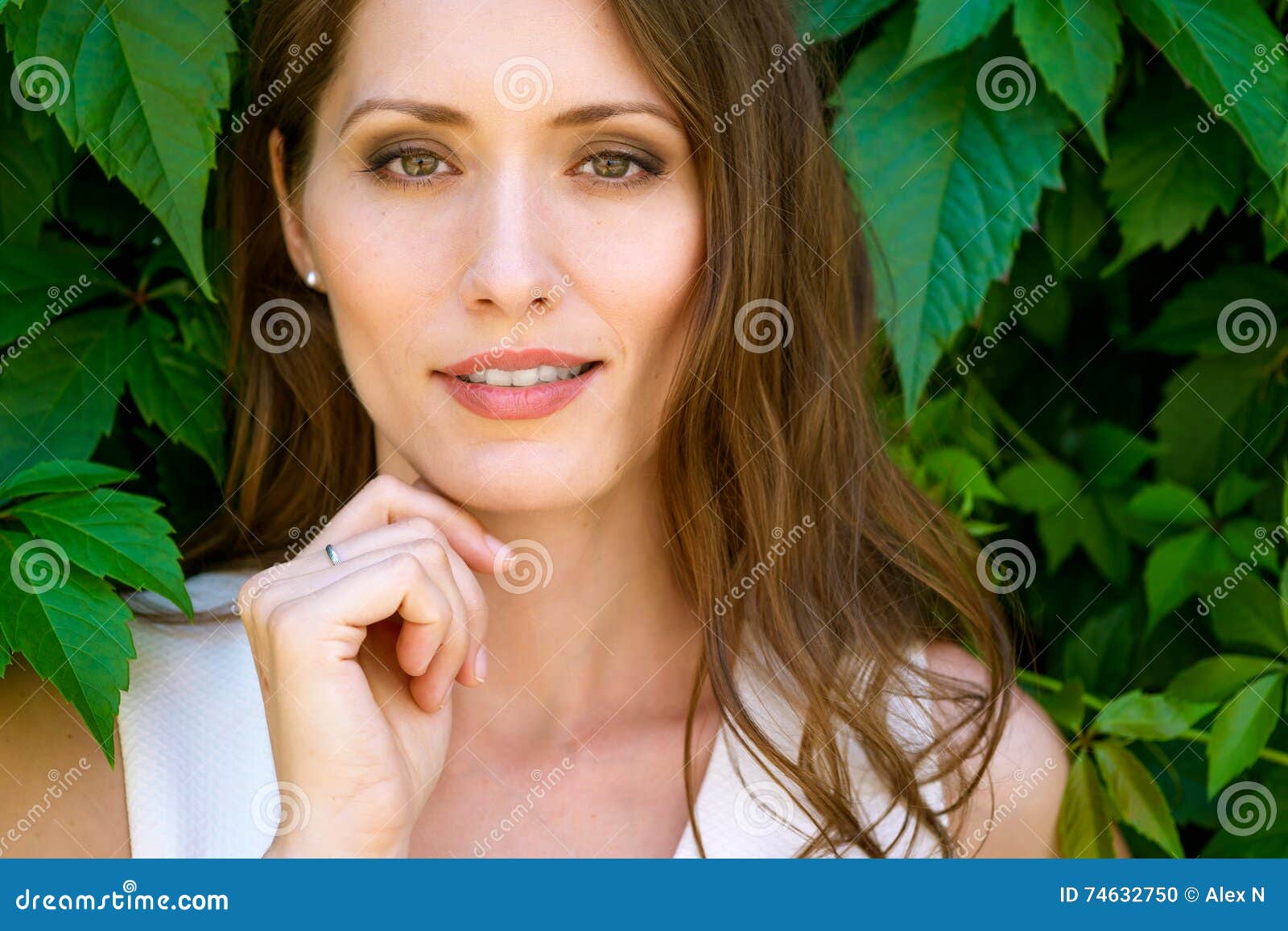 closeup portrait of young beautiful brunette woman on leaves background