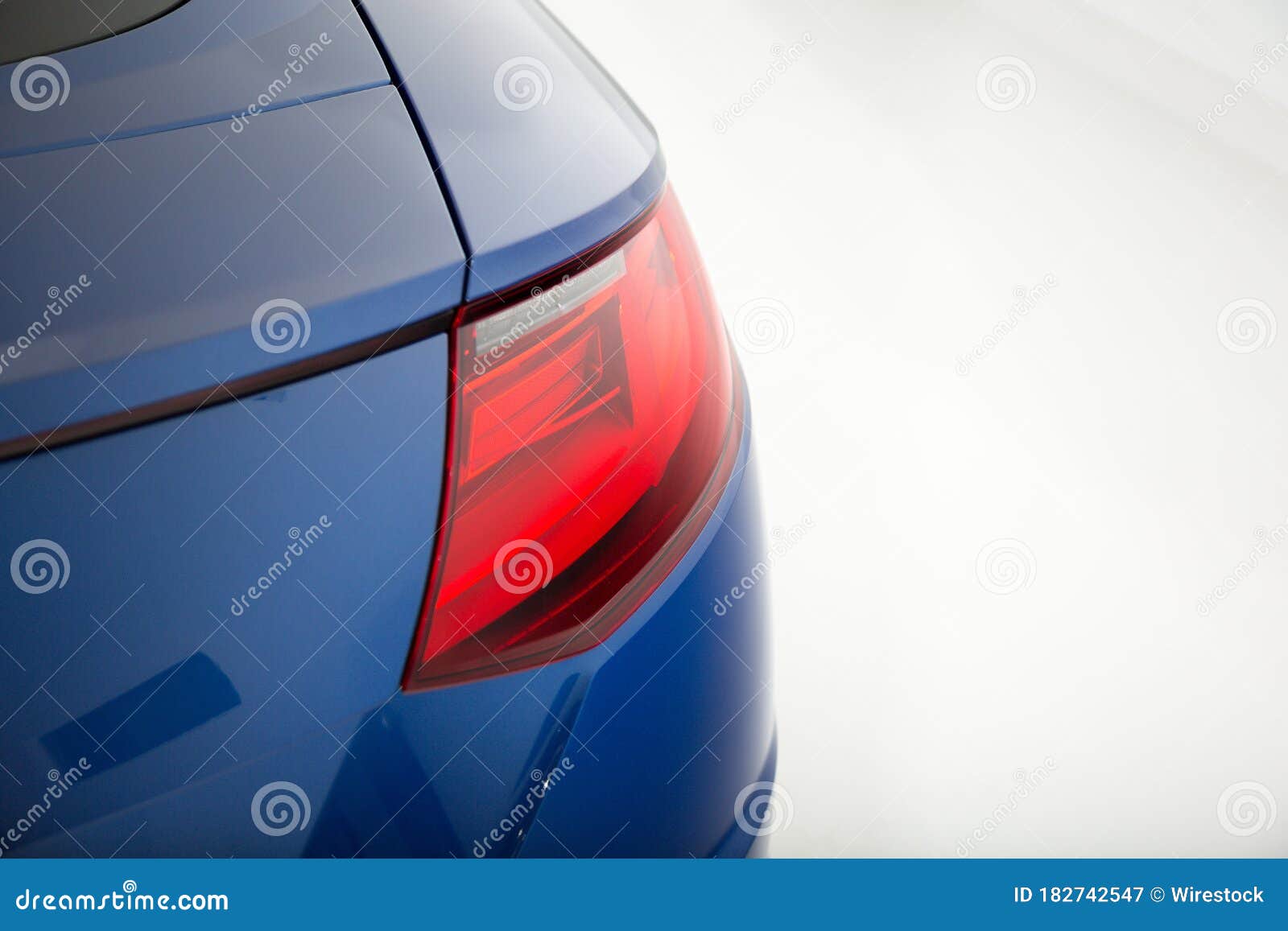 Closeup of a Red Tail Light of a Blue Luxury Car Isolated on a Grey