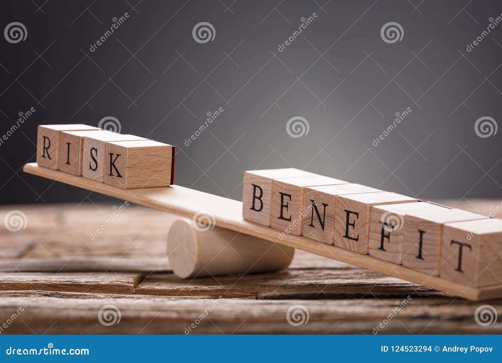 closeup of risk and benefit wooden blocks on seesaw