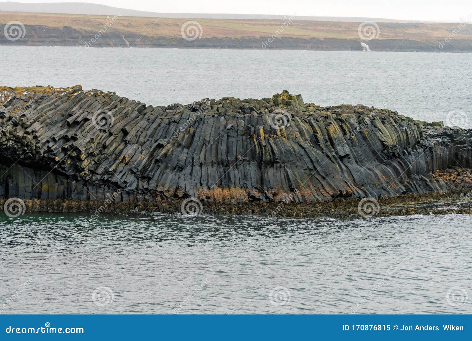 closeup shot of rocky basalt volcanic textured columns in kalfshamarsvik in iceland during heavy rain and foggy weather.