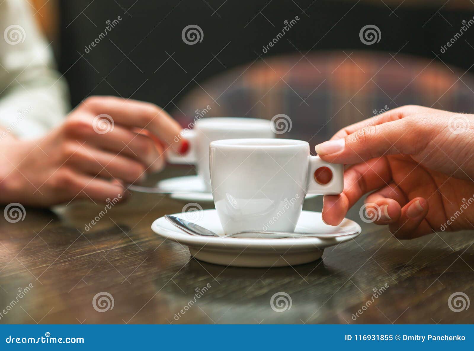 two people holding cups of coffee sitting in cafeteria.