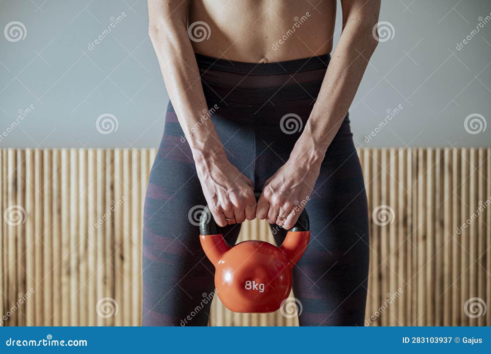 closeup view of a fit woman in sportswear holding 8 kilograms kettlebell weight