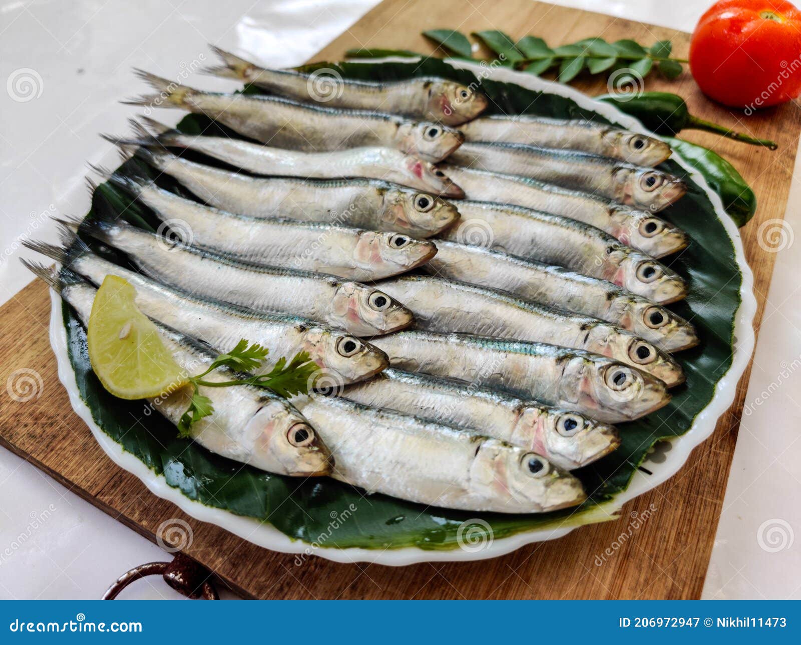 closeup view of fresh indian oil sardine decorated with herbs and vegetables selective focus.white background