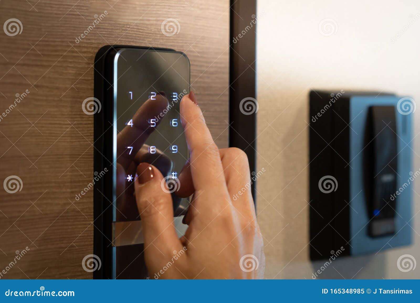 closeup of a woman`s finger entering password code on the smart digital touch screen keypad entry door lock in front of the room